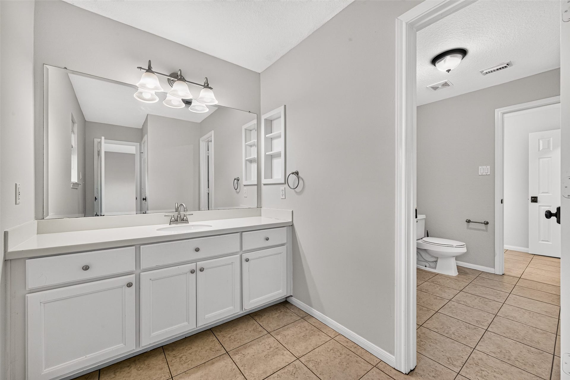 7707 Stone Arbor Drive, Sugar Land, TX 77479 A PRACTICAL JACK & JILL BATH! Connecting Bedrooms #2 & #3, Bath #2 features separate vanity areas, allowing each bedroom convenient access to its own sink, countertop & cabinetry. This first vanity offers generous storage, a large mirror & built-in shelving for keeping everyday essentials organized.