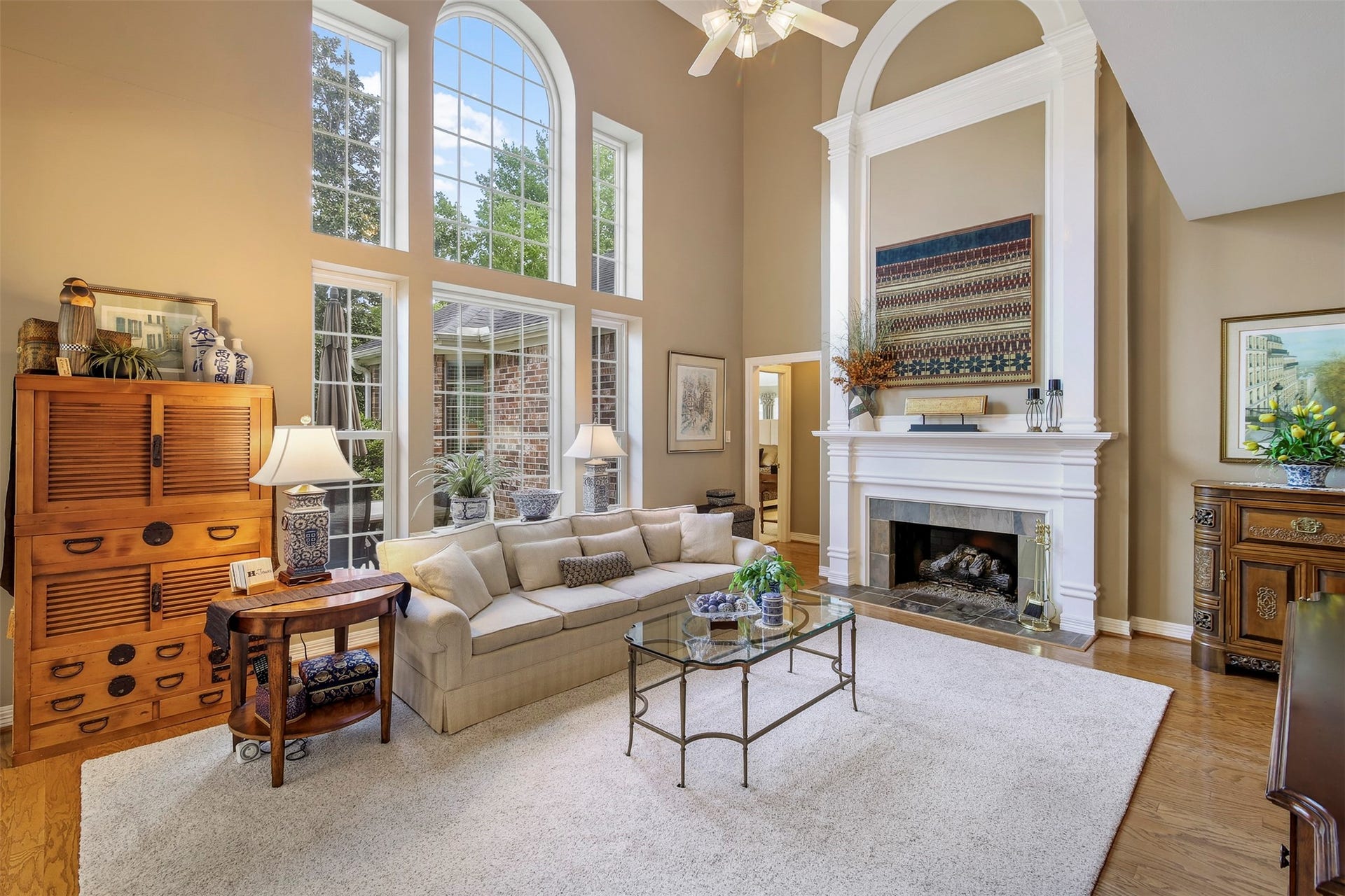 1414 Forest Bend, Sugar Land, TX 77479 Two story family room with wood floors and gas log fireplace. The fireplace has stone surround and mantle with two story trim detail.