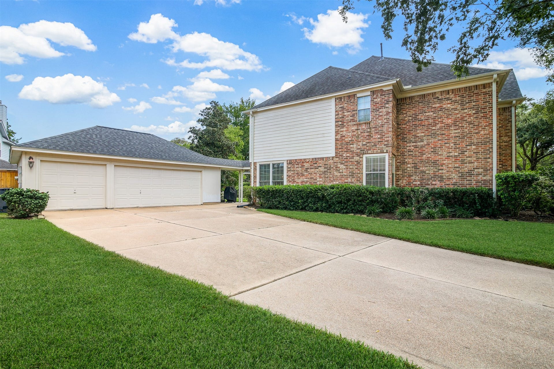 1414 Forest Bend Drive, Sugar Land, TX 77479 View of the large double driveway with 3 car detached garaged. *Grass has been virtually enhanced*