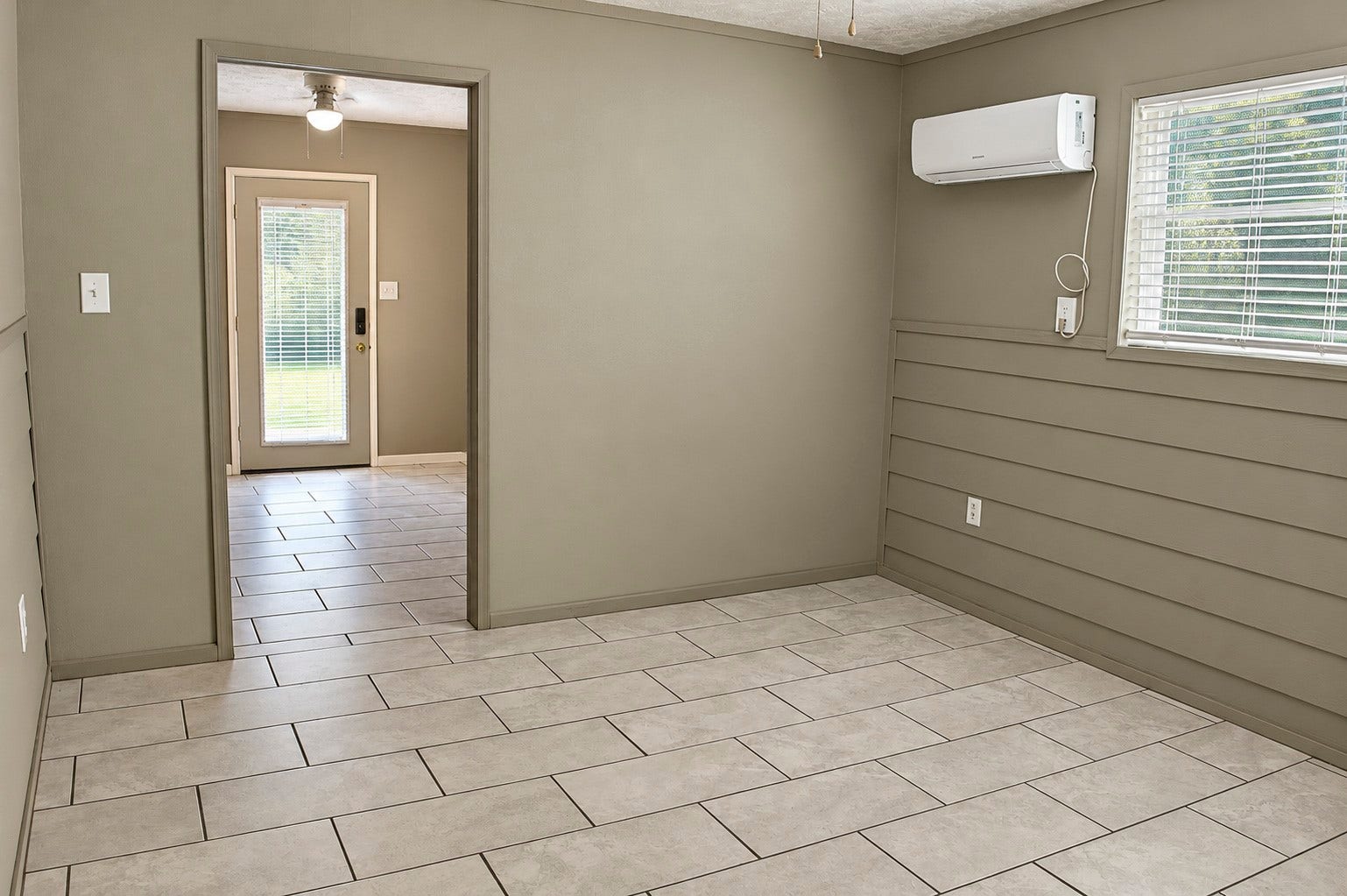 Bright, airy multiuse room in the barn with neutral tile flooring, a window for natural light, and a mini-split AC for comfort.