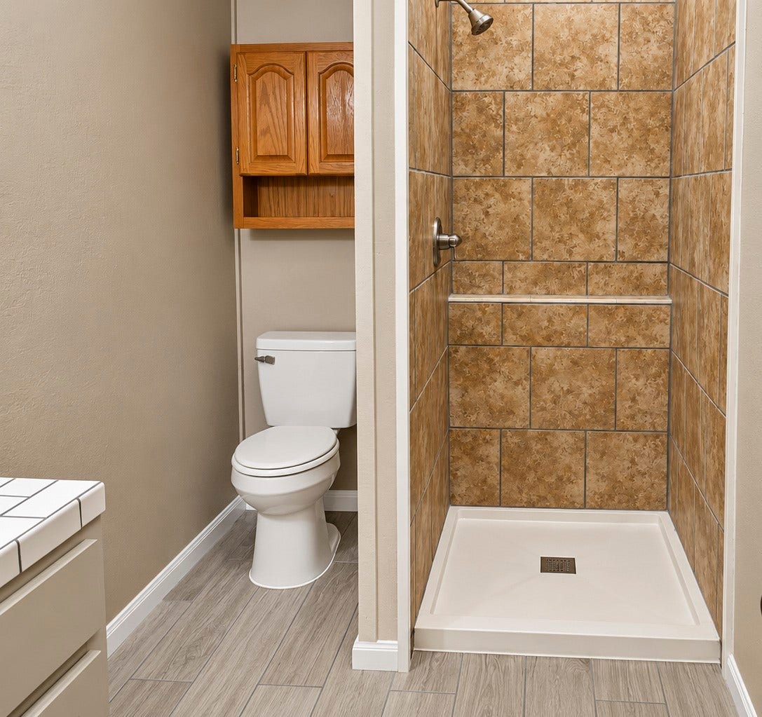 Bathroom with a tiled walk-in shower, sleek wood-look flooring, and a convenient storage cabinet above the toilet.