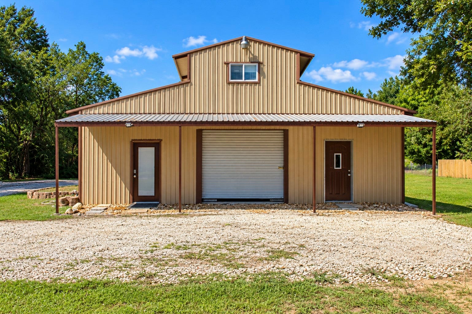 Spacious metal barn building with a large central garage door and two side entry doors to multipurpose quarters, and a 3 quarter on the 2nd floor. Ideal for storage or workshop use.