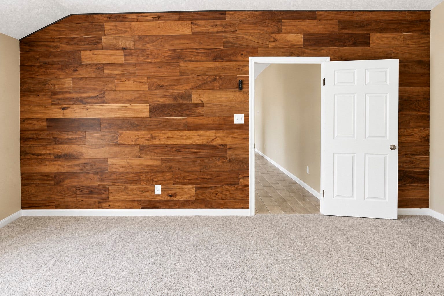 A cozy primary bedroom features a stunning wood accent wall and an inviting open doorway leading to the livingroom.