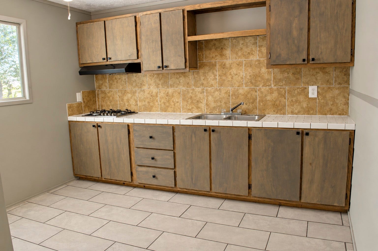 Quarter's kitchen with rustic wooden cabinets, a sleek cooktop, and a warm tile backsplash, offering both functionality and style.