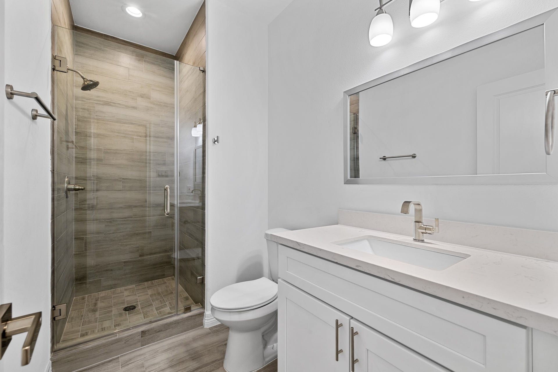 The secondary bathroom also offers a walk-in shower with gorgeous tile flooring, and quartz countertops on beautiful cabinetry with stainless fixtures.