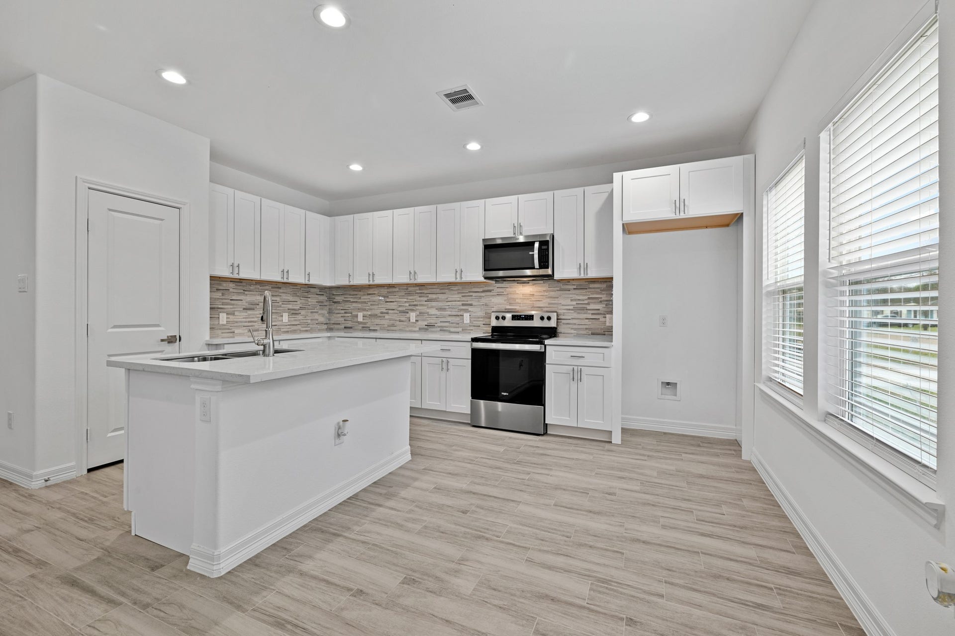 In the amply spaced kitchen, note the elegant mosaic tile backsplash surrounding the beautiful stainless and black oven and matching microwave. I just love how the Quartz countertops POP against the new cabinets and stainless fixtures.