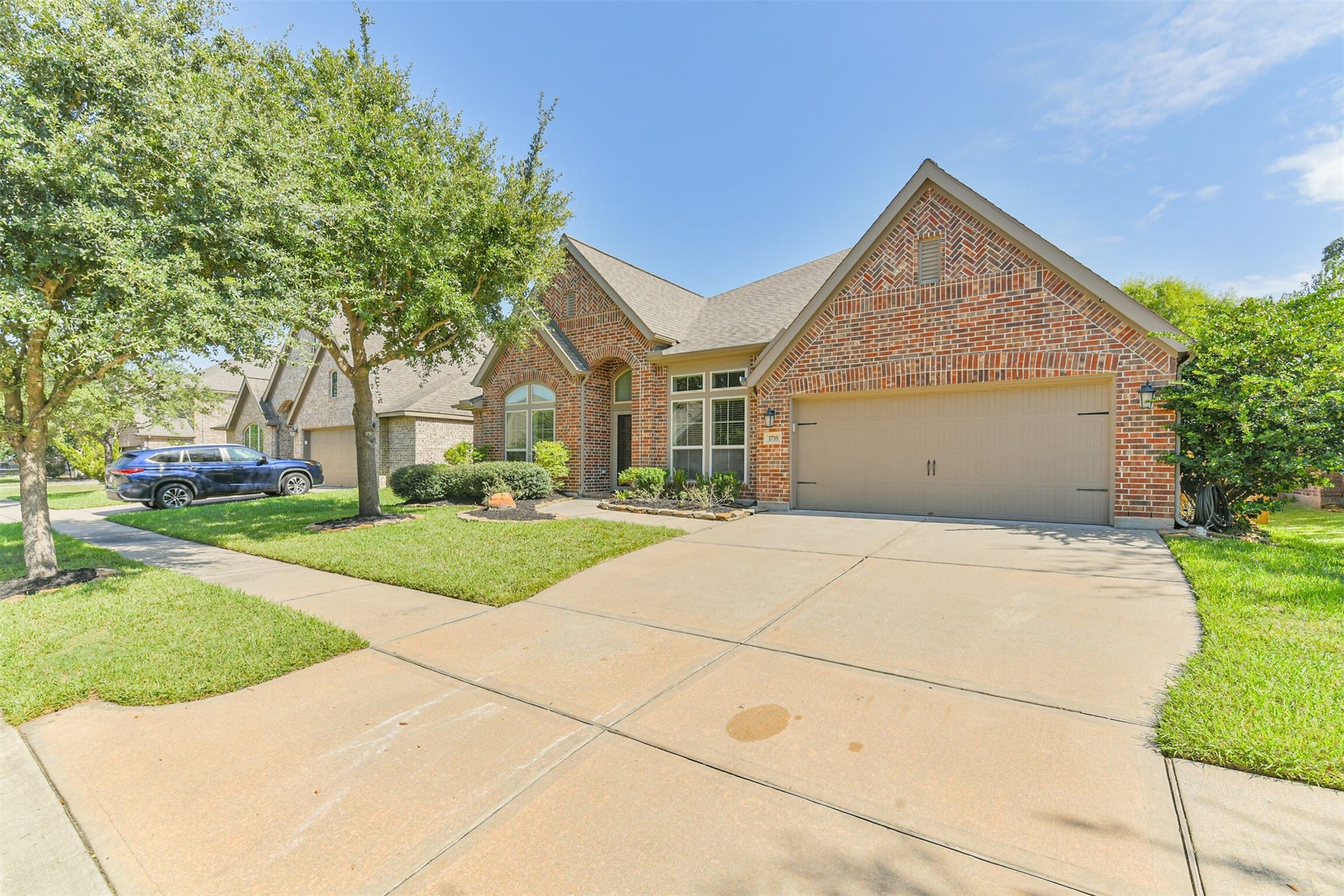 1735 Wickham Reach Drive, Spring, TX 77386 Another exterior view highlighting the spacious driveway and well-maintained front yard.