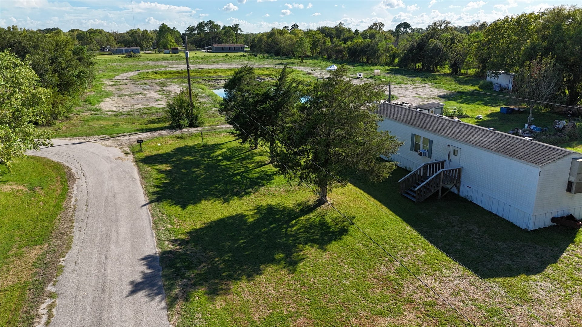 Mobile home nestled on a spacious lot with lush greenery, offering a peaceful countryside setting. Ideal for those seeking tranquility and room to grow.