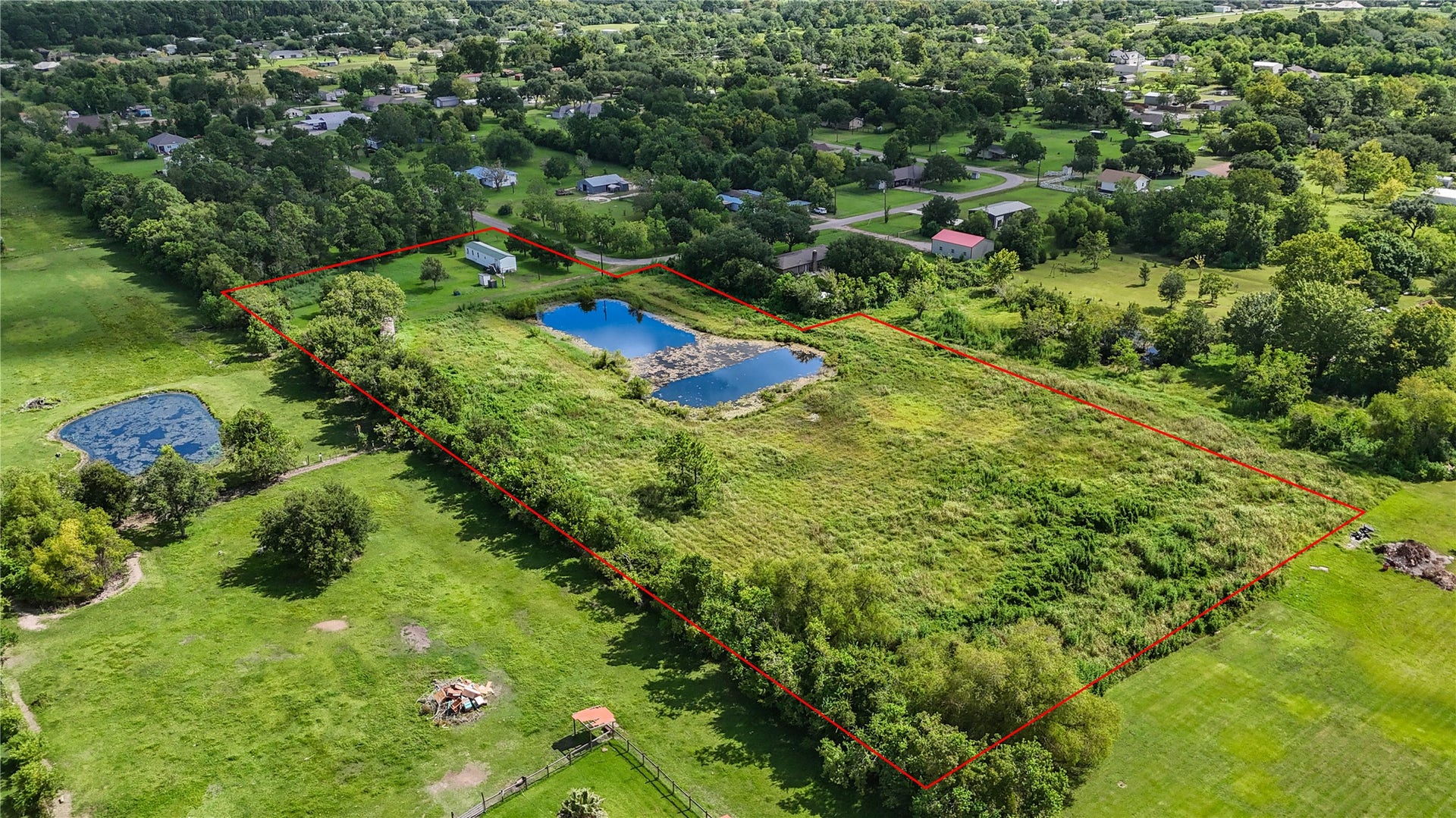 Expansive property with a delineated boundary, featuring a serene pond and lush greenery, offering ample space for outdoor activities and relaxation.