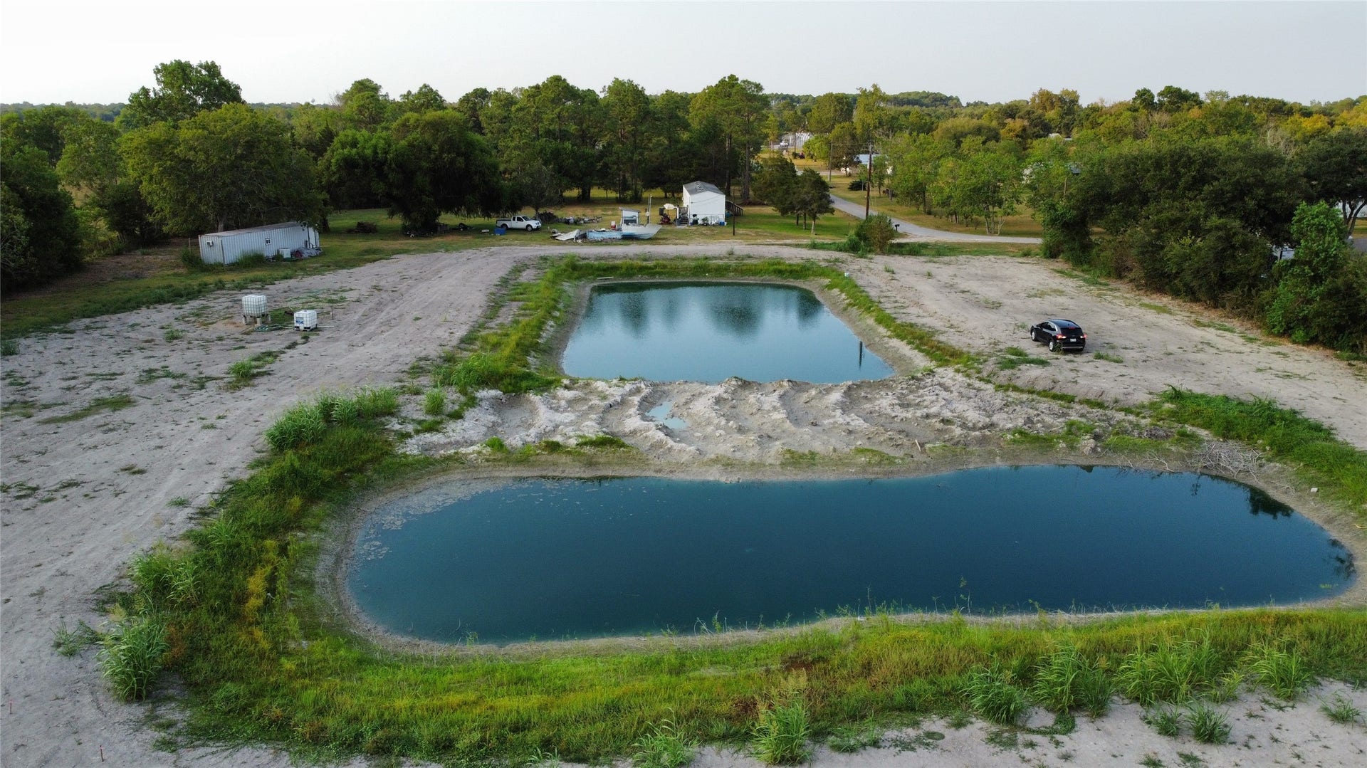 Expansive property featuring a serene pond surrounded by natural greenery, offering ample space for development or recreation in a tranquil setting.