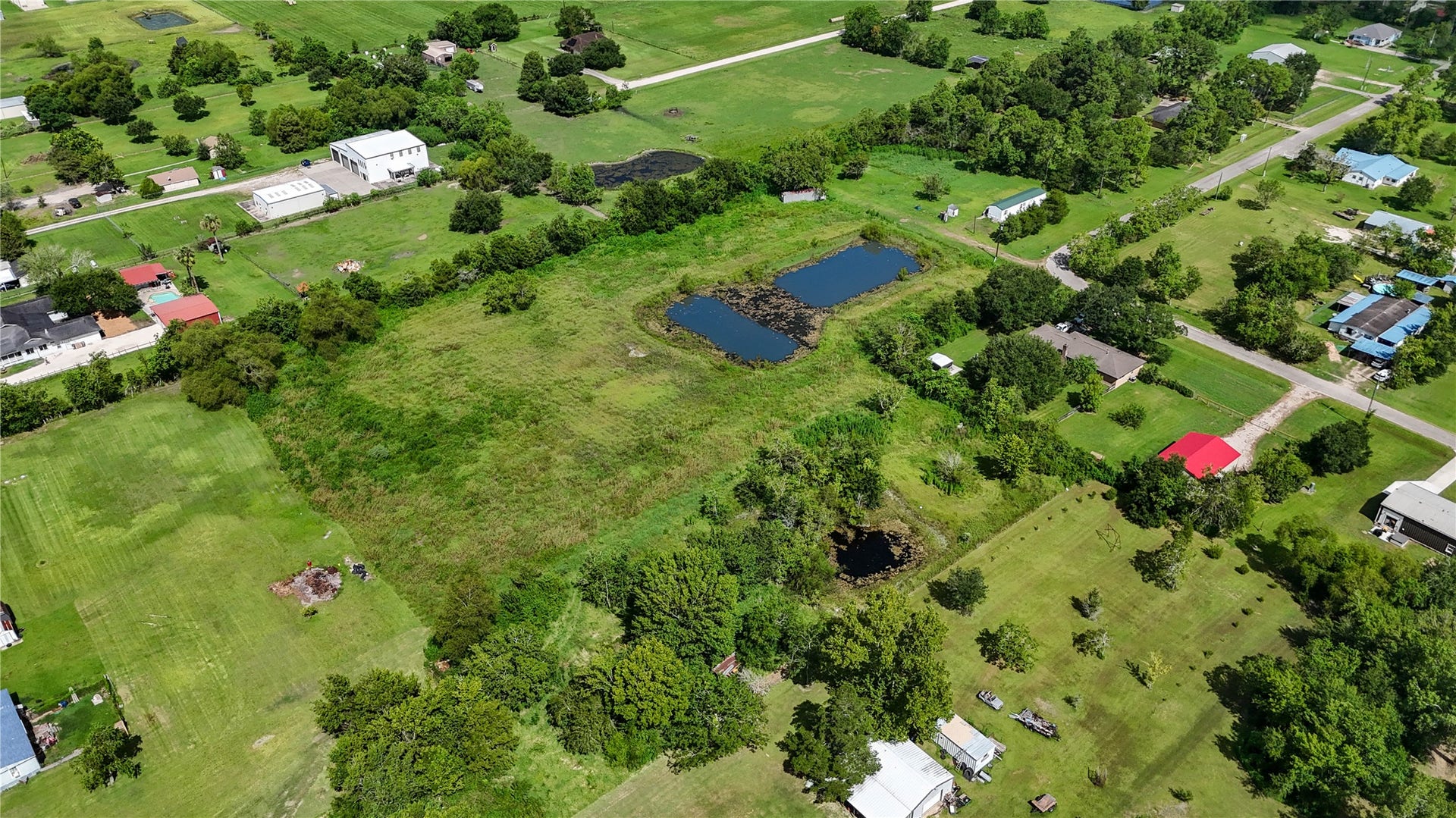 Expansive rural property featuring a picturesque pond, surrounded by lush greenery and offering serene countryside views, perfect for a peaceful retreat or development opportunity.