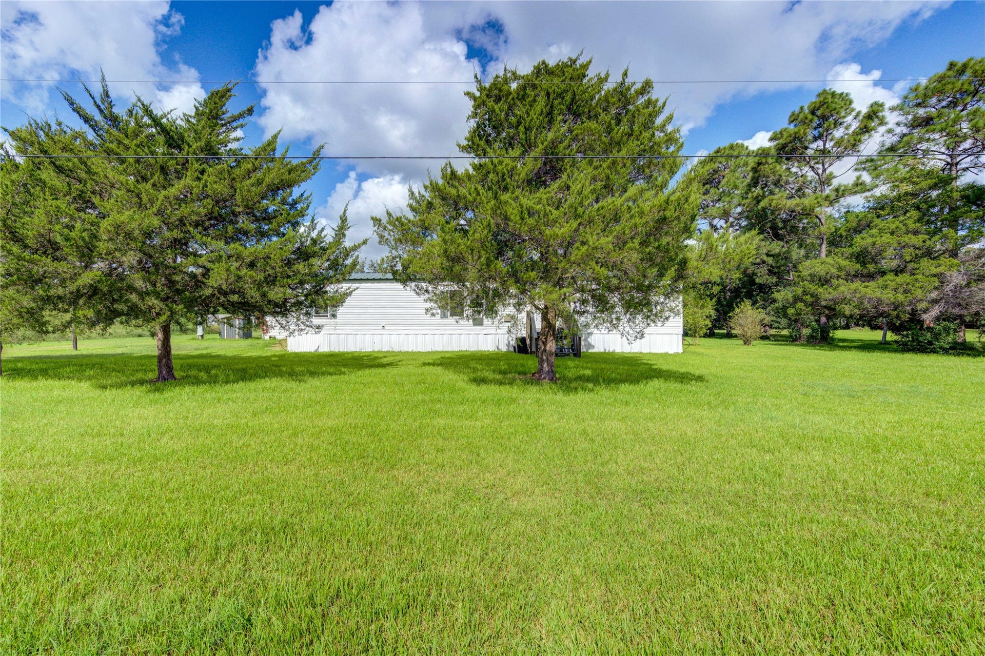Mobile home set on a spacious lot, surrounded by lush greenery and open spaces. Ideal for those seeking tranquility and privacy.