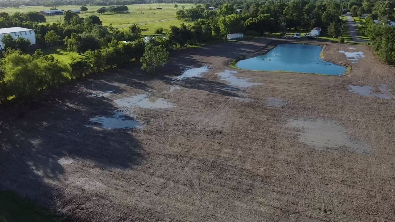Expansive open land featuring a serene pond, surrounded by lush greenery, perfect for building your dream home or a peaceful retreat.