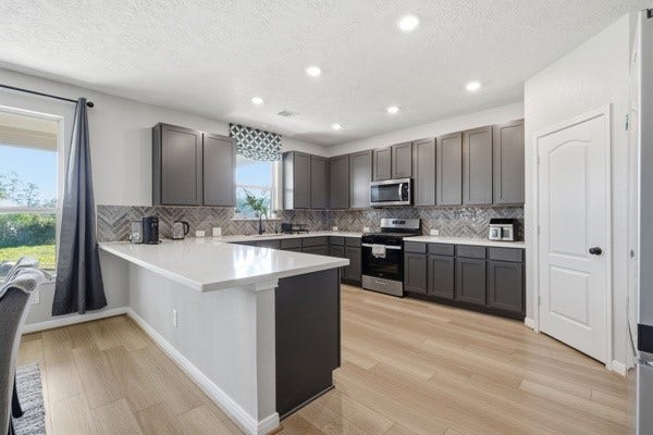 15334 Silver Breeze Lane, Houston, TX 77044 Spacious kitchen with modern gray cabinetry, stainless steel appliances, and a large island perfect for entertaining.