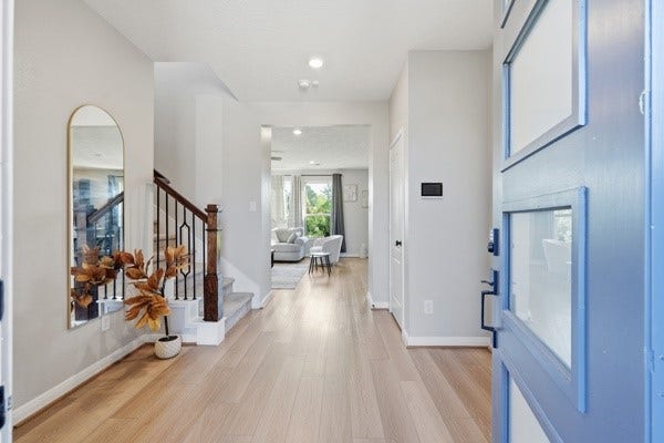 15334 Silver Breeze Lane, Houston, TX 77044 Inviting entryway with sleek hardwood floors leads to a bright, open living area. Elegant staircase and modern decor enhance the welcoming atmosphere.