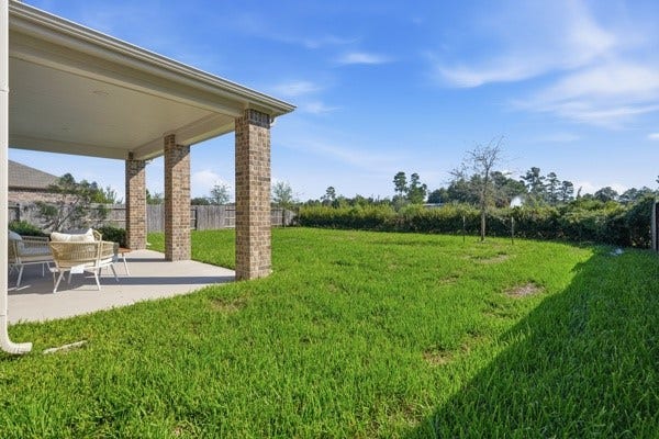 15334 Silver Breeze Lane, Houston, TX 77044 Spacious backyard with a covered patio, perfect for outdoor relaxation and entertaining, surrounded by lush greenery for added privacy.