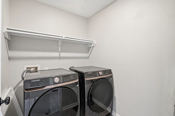 15334 Silver Breeze Lane, Houston, TX 77044 Modern laundry room featuring sleek front-loading washer and dryer with a convenient overhead shelf for storage.