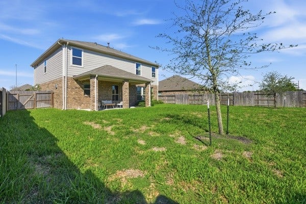 15334 Silver Breeze Lane, Houston, TX 77044 Spacious backyard with a covered patio, perfect for outdoor activities and relaxation, surrounded by a wooden fence for privacy.