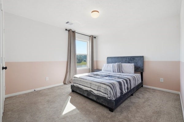 15334 Silver Breeze Lane, Houston, TX 77044 Bright and cozy bedroom featuring a soft carpet, modern bed with striped bedding, and a large window allowing plenty of natural light.