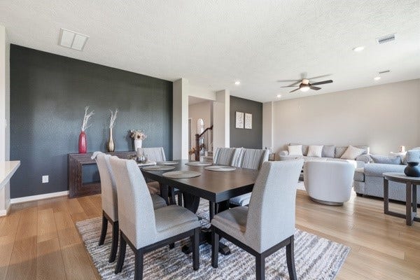 15334 Silver Breeze Lane, Houston, TX 77044 Spacious open-concept living and dining area featuring modern decor, a sleek black accent wall, and abundant natural light, perfect for entertaining and relaxation.