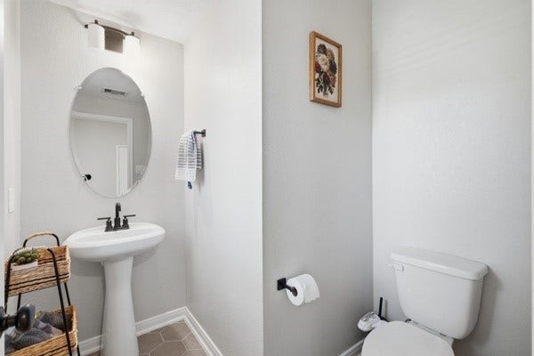 15334 Silver Breeze Lane, Houston, TX 77044 Charming powder room featuring a sleek pedestal sink and modern fixtures, complemented by neutral tones and tasteful decor.