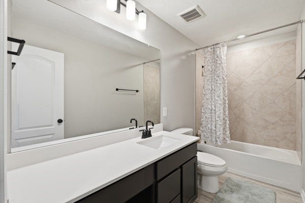 15334 Silver Breeze Lane, Houston, TX 77044 Sleek bathroom featuring a modern vanity with dual sinks, elegant fixtures, and a stylish shower-tub combo with tiled surround.