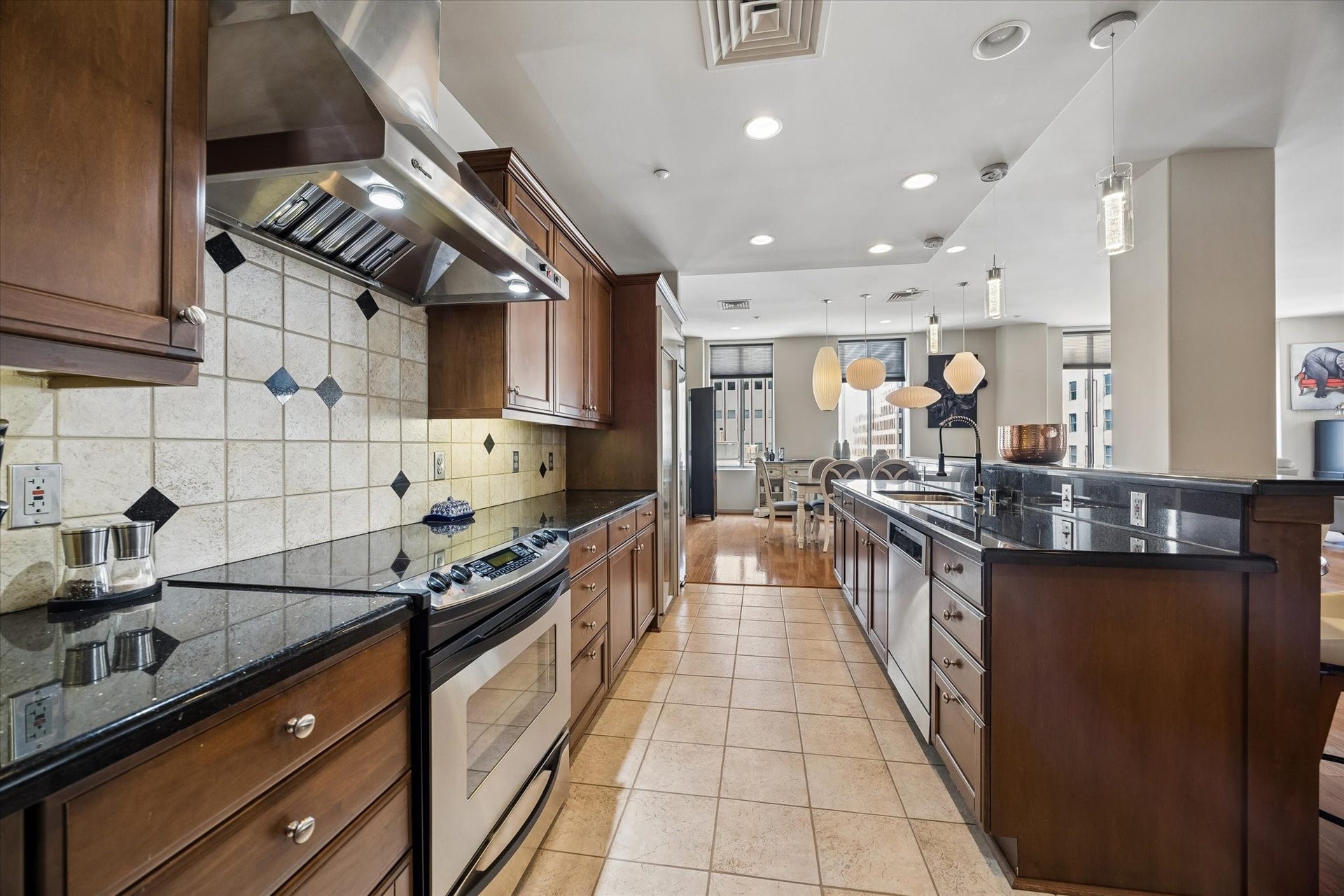 914 Main Street, #801, Houston, TX 77002 Elegant kitchen featuring rich wood cabinetry, sleek granite countertops, and modern stainless steel appliances, seamlessly flowing into a bright, open living space.