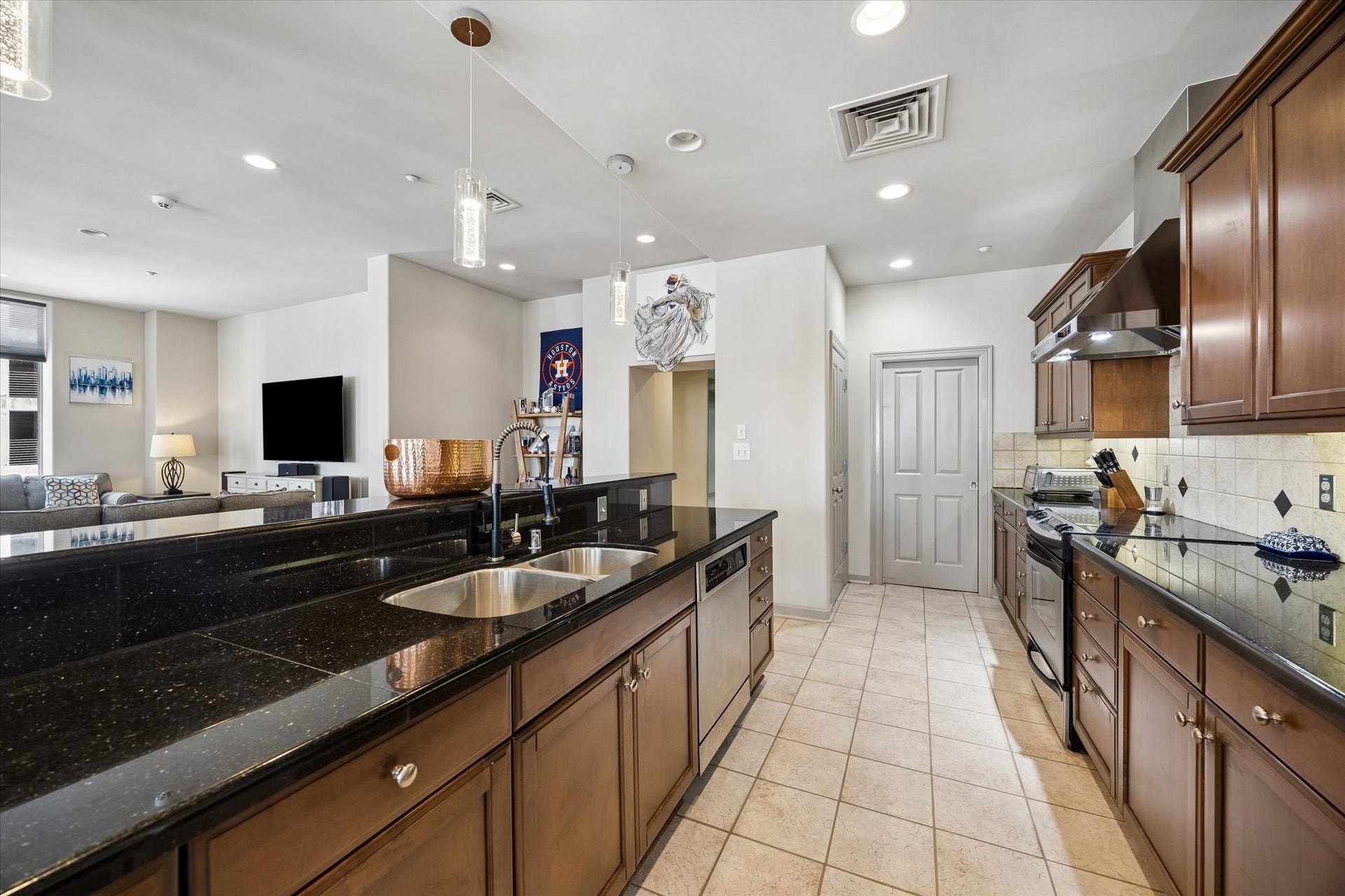 914 Main Street, #801, Houston, TX 77002 Spacious, modern kitchen with sleek black countertops, rich wooden cabinets, and stainless steel appliances, seamlessly connected to an inviting living area.