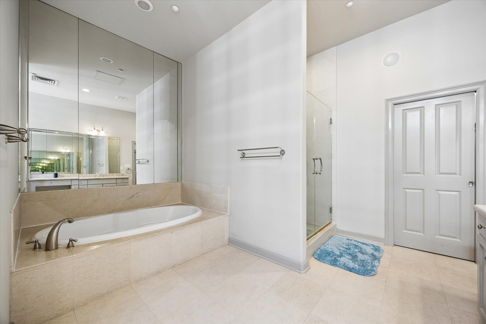 914 Main Street, #801, Houston, TX 77002 Elegant bathroom featuring a luxurious soaking tub, glass-enclosed shower, and sleek vanity with ample mirror space.