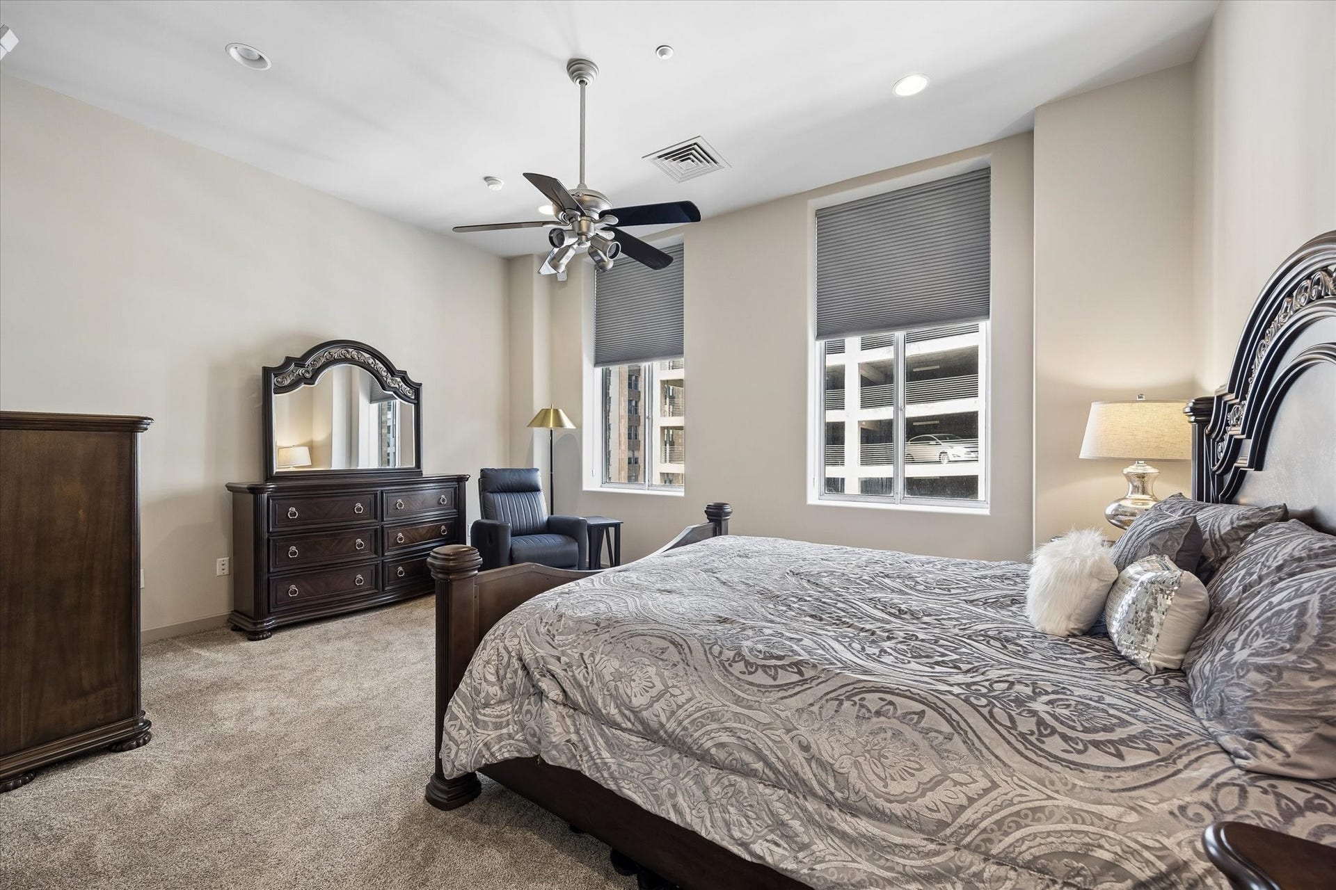 914 Main Street, #801, Houston, TX 77002 Spacious primary bedroom featuring elegant dark wood furniture, plush carpeting, and ample natural light from large windows.