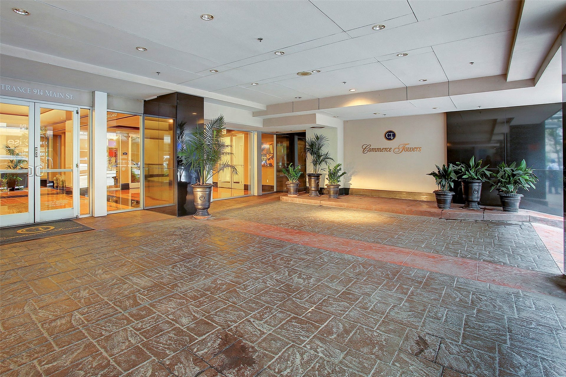 914 Main Street, #801, Houston, TX 77002 Elegant entrance to Commerce Towers, featuring a covered walkway, potted plants, and well-lit glass doors for a sophisticated welcome.