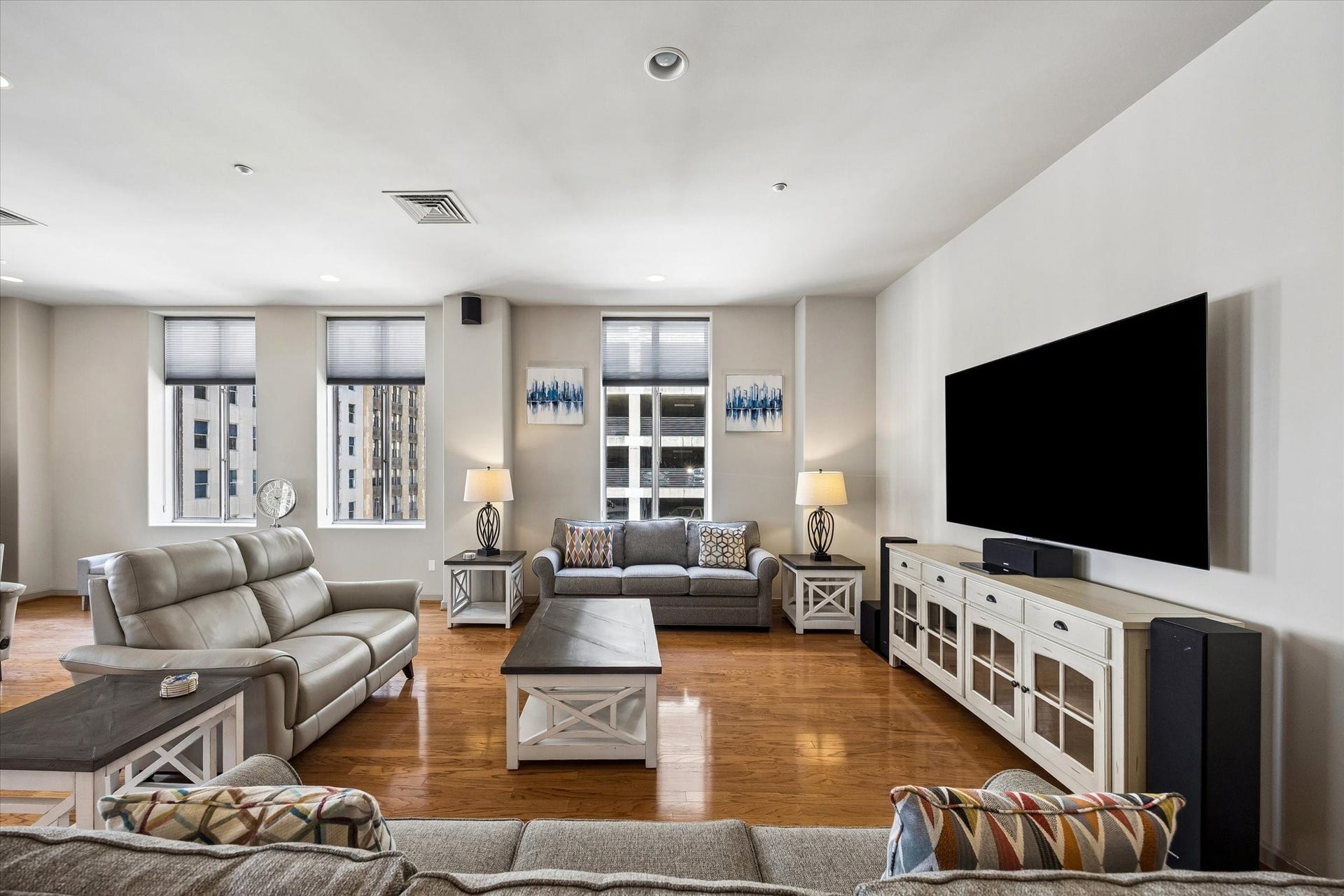 914 Main Street, #801, Houston, TX 77002 Spacious living room with elegant hardwood floors and ample natural light, featuring cozy seating arrangements, modern furnishings, and a sleek mounted TV for entertainment.