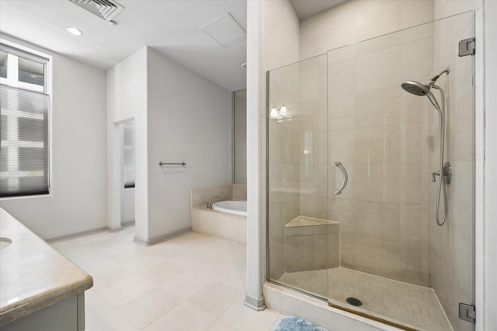 914 Main Street, #801, Houston, TX 77002 Spacious primary bathroom featuring a sleek glass-enclosed shower, elegant tile flooring, and a luxurious soaking tub for ultimate relaxation.