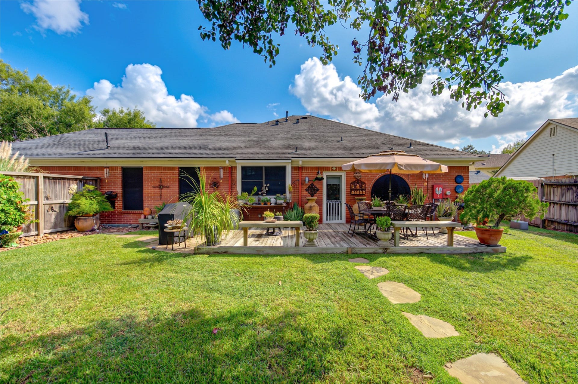 6839 Hertford Park Drive, Houston, TX 77084 A wide rear view showcases the brick exterior, deck and beautifully maintained lawn.