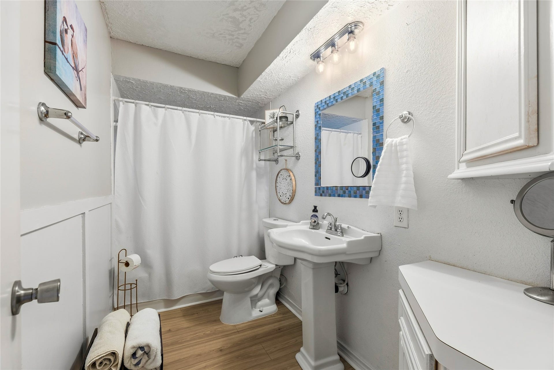 Hall bathroom with a pedestal sink, tub and shower combination, and wall storage.