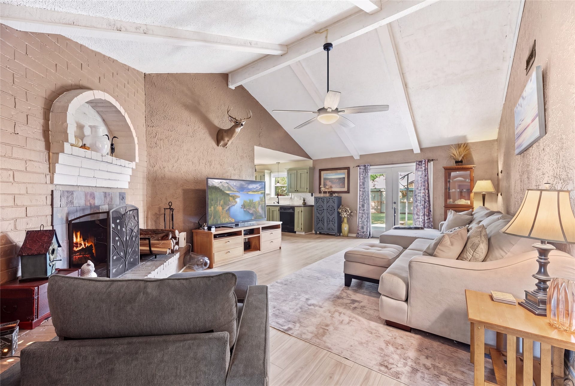 Living room with a vaulted ceiling, brick fireplace, and seating space connected to the kitchen and breakfast area.