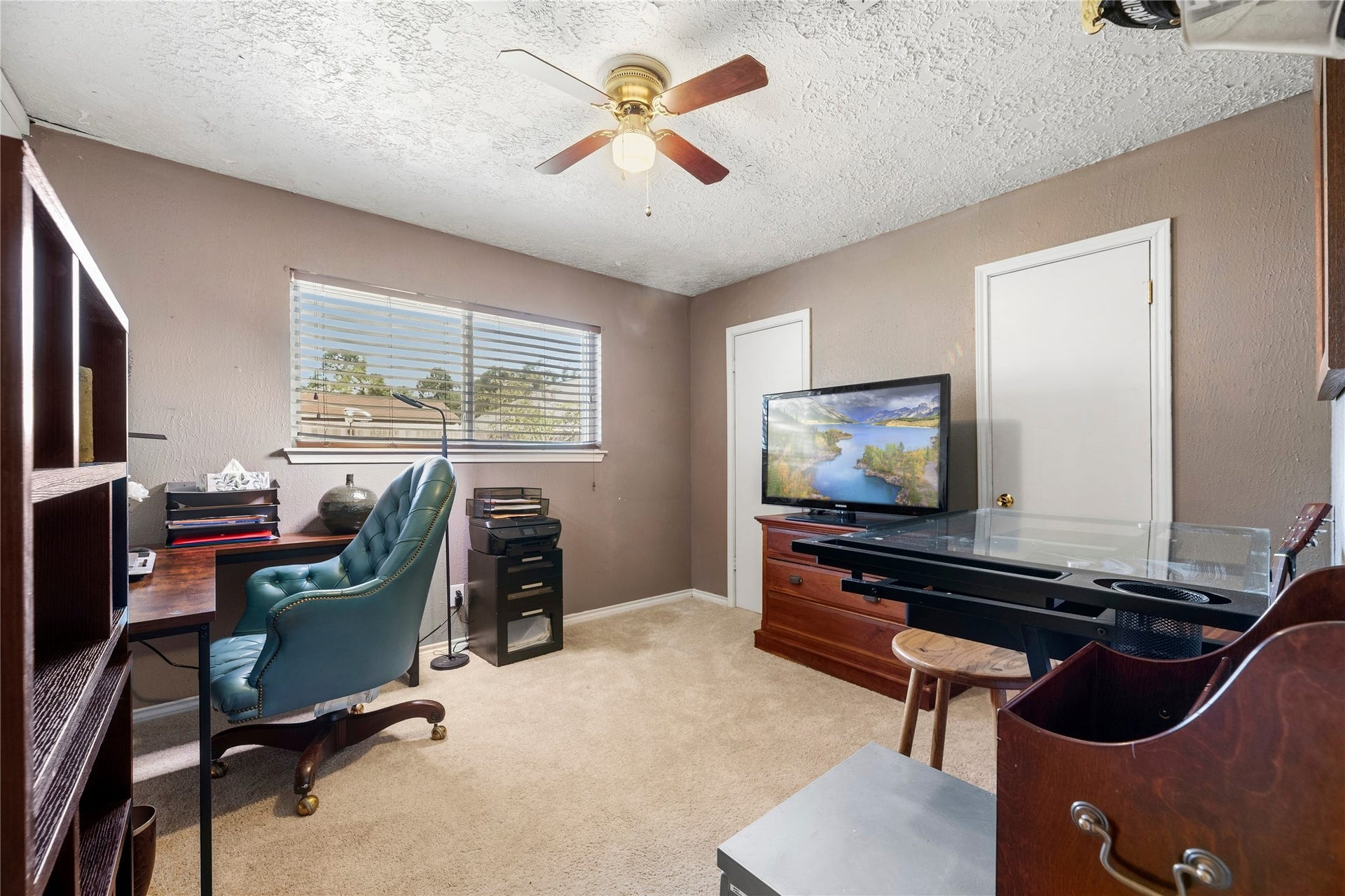 Original bedroom photo showing its current use as an office, with desk space and a window. A virtually staged bedroom version appears earlier in the gallery.