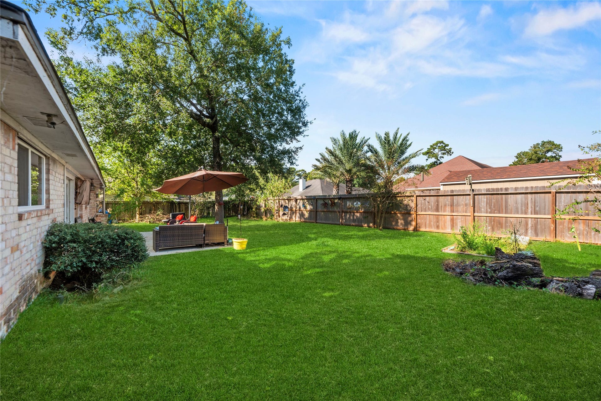 Original side view of the backyard, including the existing garden bed, lawn, trees, and fence before virtual clearing.