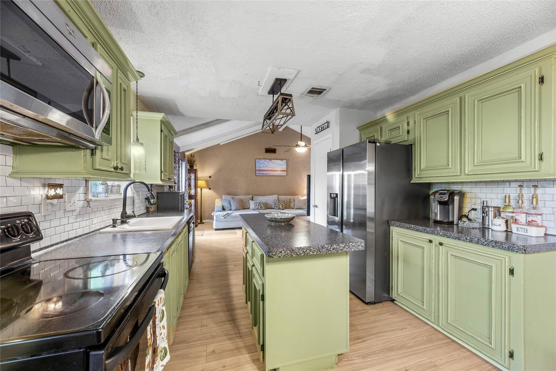 View through the kitchen toward the living room, showing how the island and cabinetry fit into the layout.