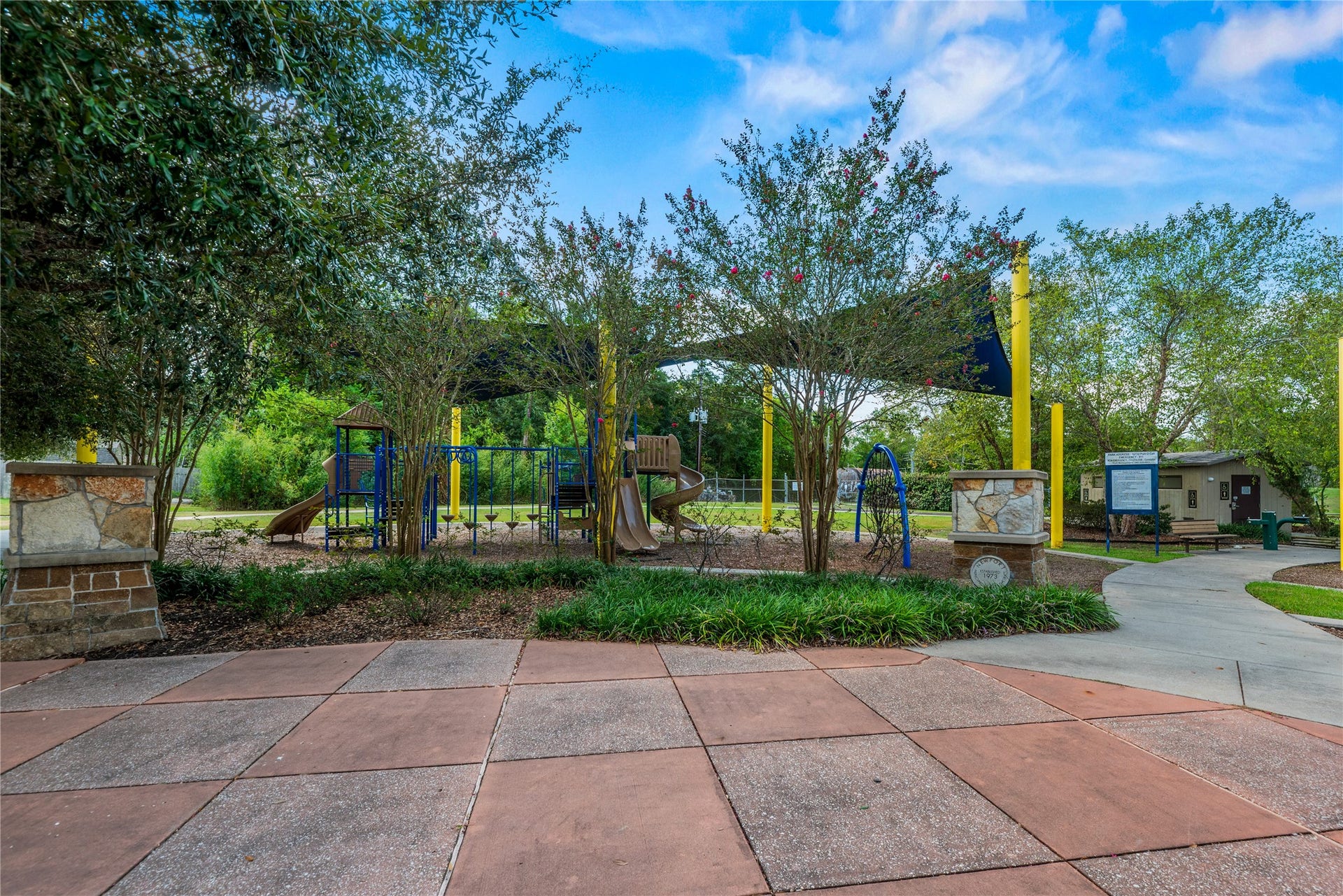 Community playground with a covered pavilion, walking paths, and mature shade trees.