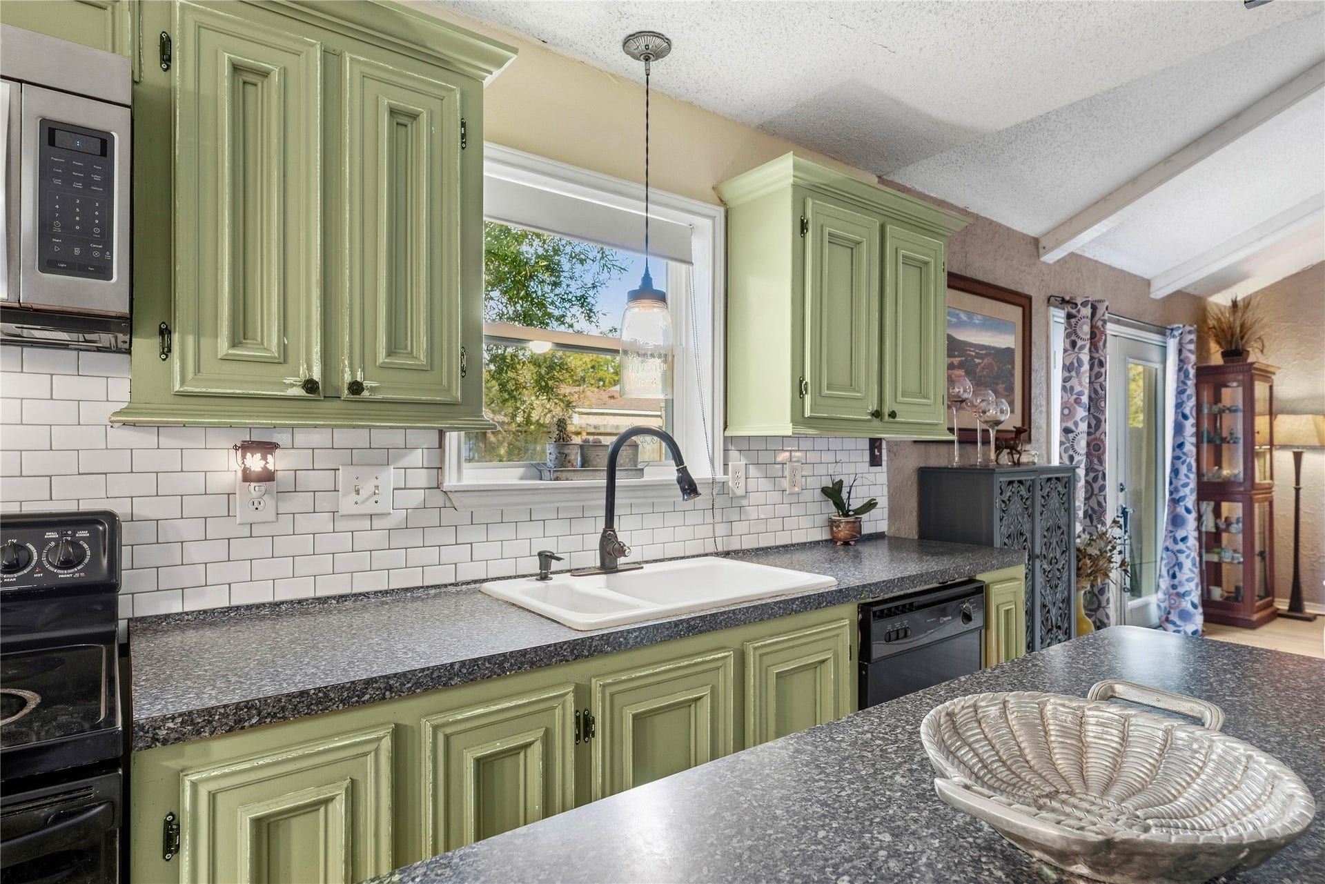 A window above the kitchen sink brings in natural light, with cabinets and counter space nearby.