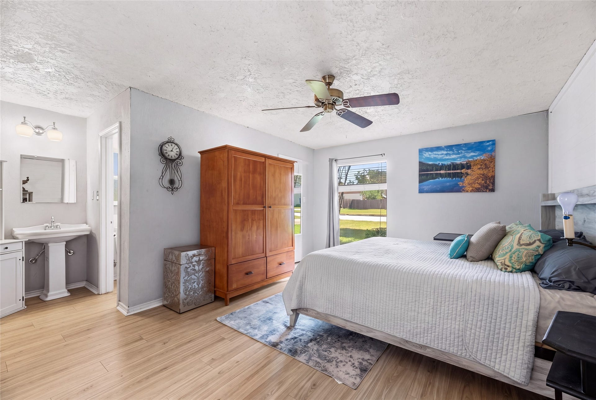 Primary bedroom with natural light, a ceiling fan, and wood-look flooring.