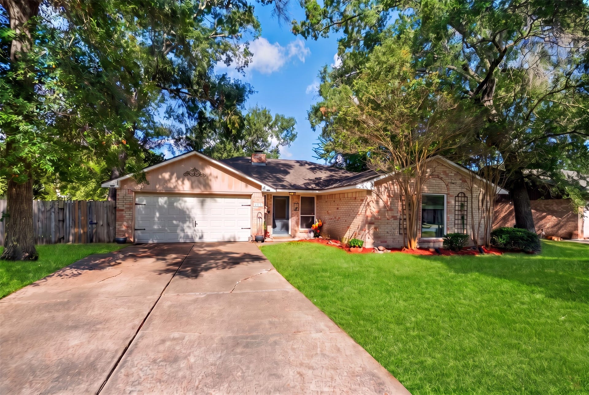 Front elevation showing the brick exterior, garage, and entry tucked beneath the mature tree canopy.