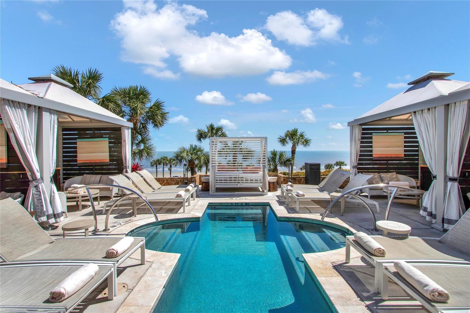 Luxurious poolside oasis with elegant cabanas and stunning ocean views, perfect for relaxation and entertaining.