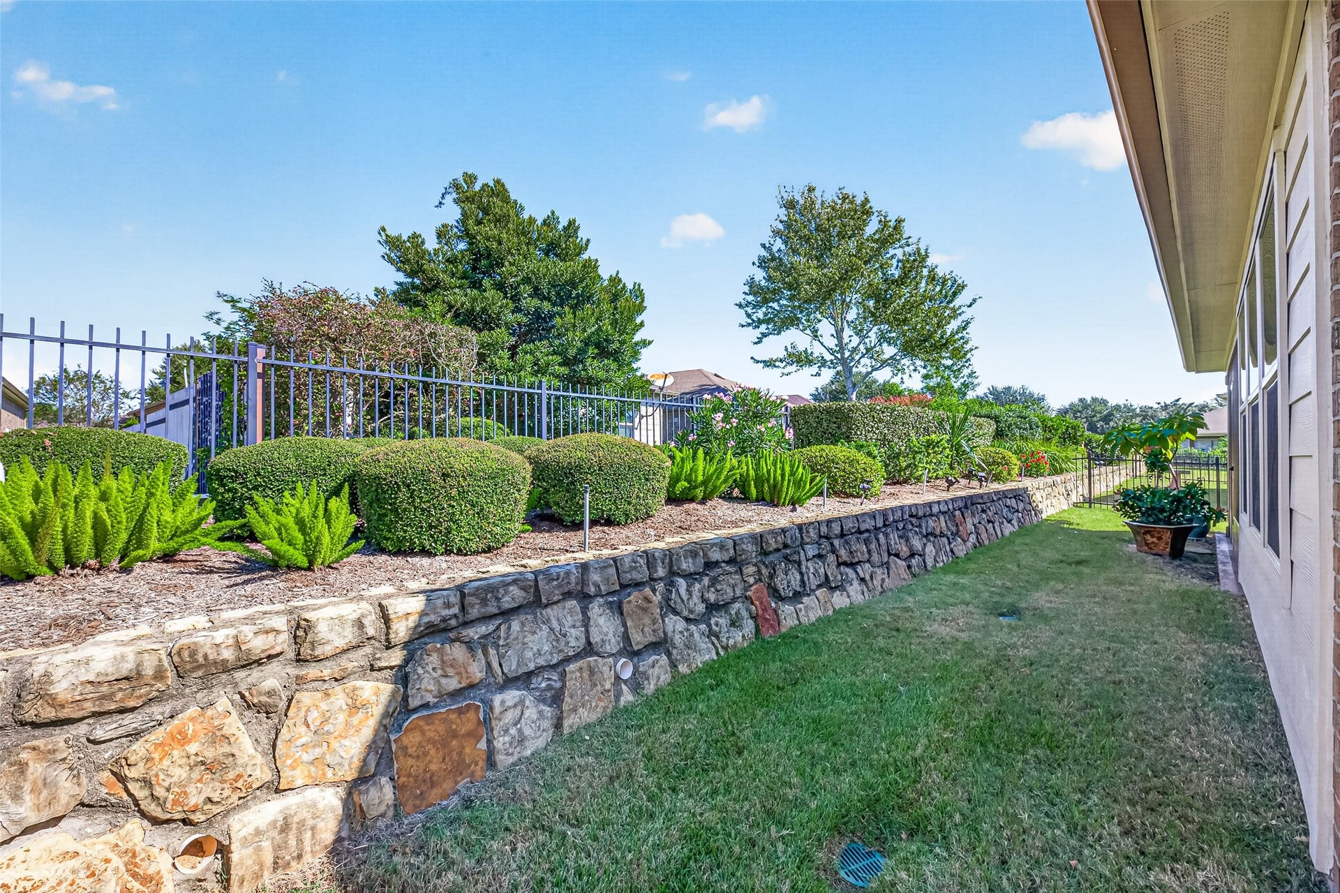 1126 Oleander Way, Richmond, TX 77469 A stone retaining wall adds character to the landscaped backyard.