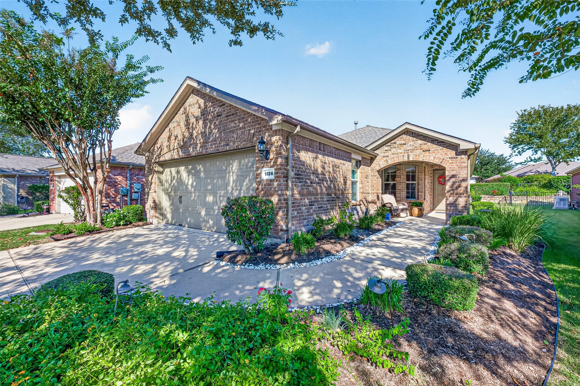 1126 Oleander Way, Richmond, TX 77469 Welcoming brick exterior framed by mature trees and colorful landscaping.