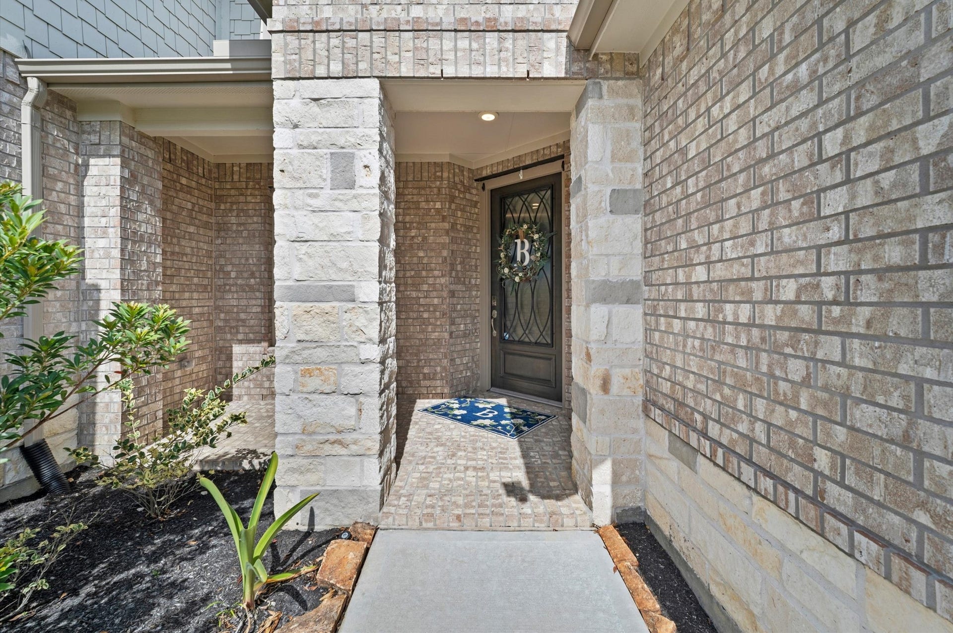 Beautiful brick entryway with elegant glass-paneled front door, and a front porch.