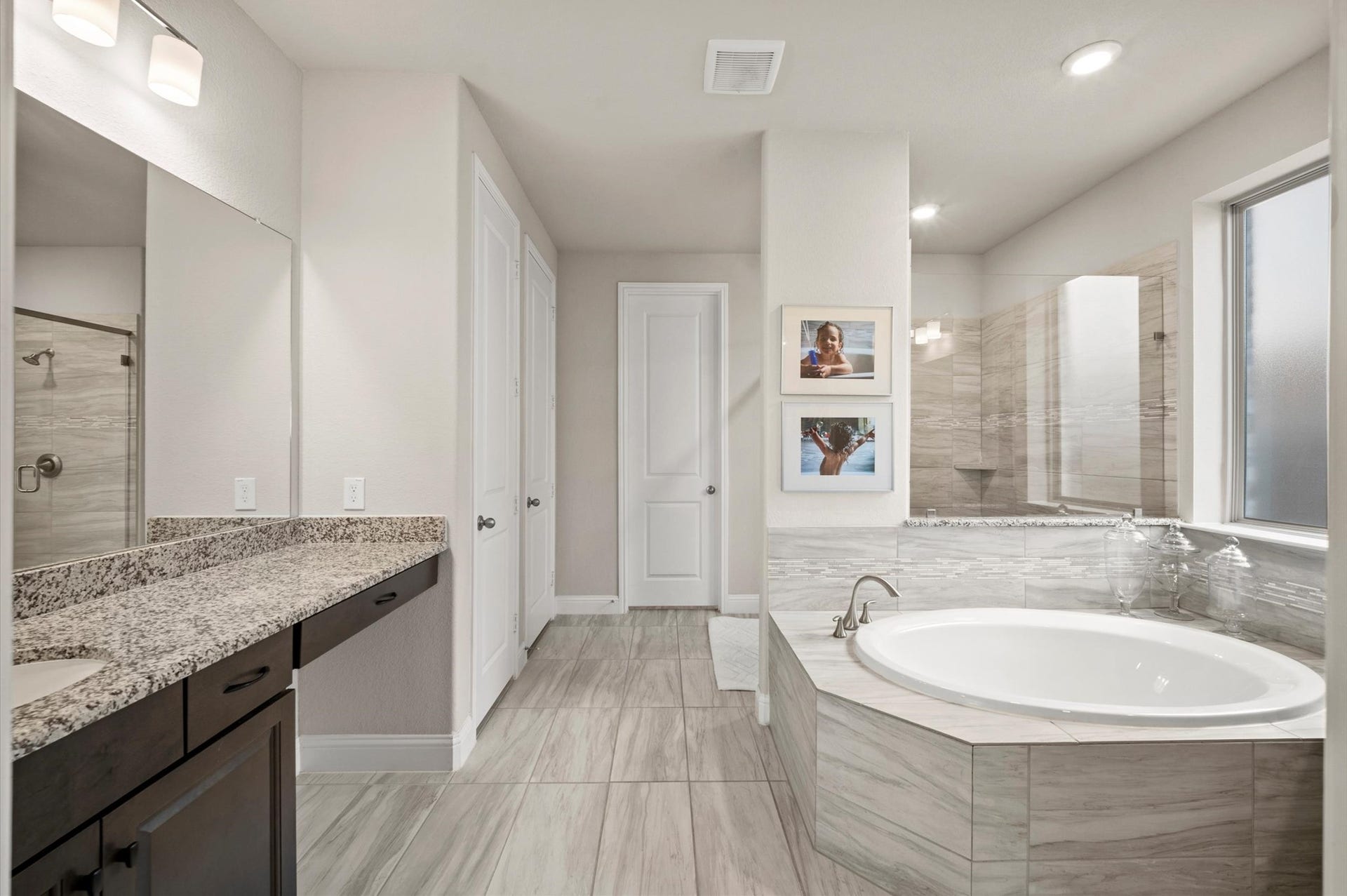 Primary bathroom featuring a soaking tub, modern walk-in shower, and elegant granite countertops, complete with his and hers closets!