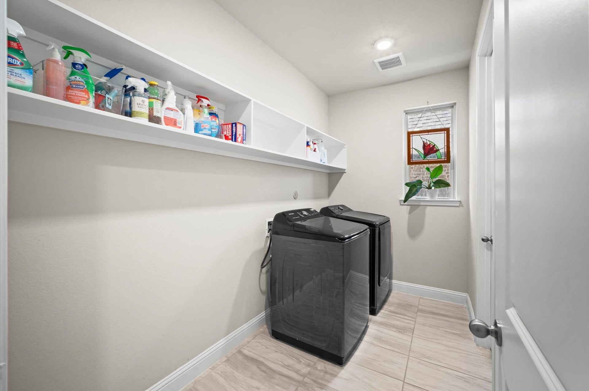 Laundry room with ample shelving, and a window for natural light.