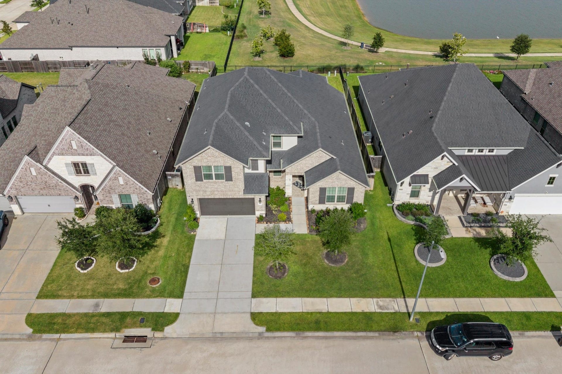 Charming two-story home with a spacious driveway, elegant brick facade, and manicured front lawn. Located in a serene neighborhood with a picturesque view of the lake.